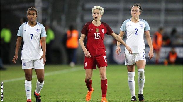 Megan Rapinoe of United States walks upfield ahead of Nikita Parris and Lucy Bronze of England during the SheBelieves Cup