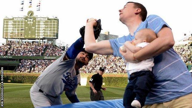 Father catches ball at Major League Baseball game with son in hand