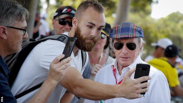 Sir Jackie Stewart poses for a photograph with a fan