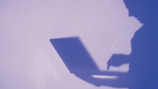 Man in silhouette looking at laptop