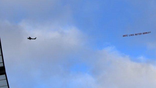 A banner reading 'White Lives Matter Burnley' is flown above Etihad Stadium before a Premier League match between Manchester City and Burnley