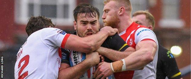 Widnes' Ted Chapelhow is wrapped up in a tackle against St Helens