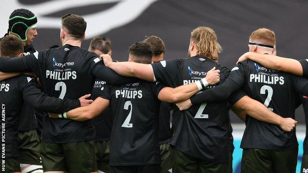 Ospreys players in a huddle with their tribute to Ifan Phillips before a 21-13 defeat to Sale