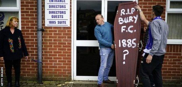 Joy Hart (left) chained herself to the stand that bears her father's name at Gigg Lane while fans brought a coffin commemorating the death of the club