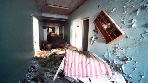 a bed is abandoned in a hotel corridor with peeling paint