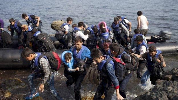 Syrian and Afghan refugees jump off a dinghy as they arrive on the Greek island of Lesbos