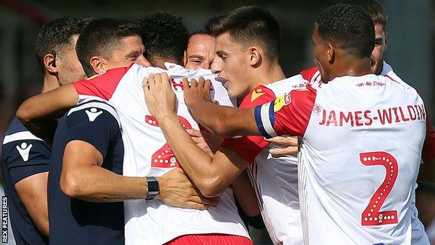 Stevenage players celebrate with Mark Sampson