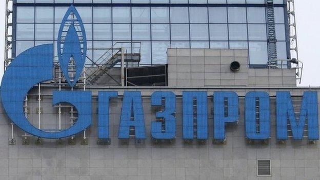 An employee stands near a window, with the company logo of Gazprom installed on a building, at the headquarters of the Russian natural gas producer in Moscow