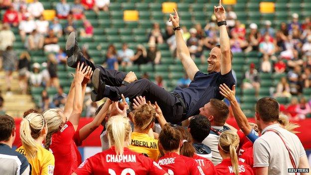 Head Coach Mark Sampson is hoisted in the air by the team.