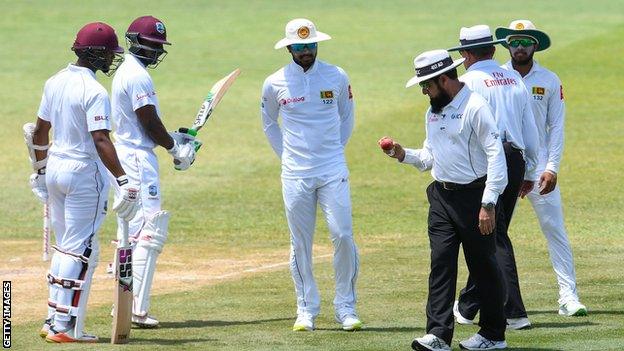 Umpire Aleem Dar inspects the ball as Sri Lanka captain Dinesh Chandimal (centre) looks on