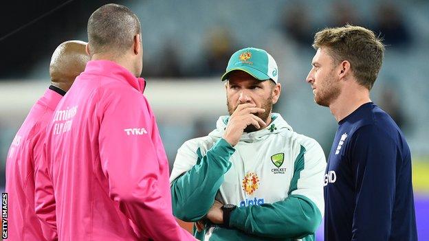 The umpires speak to captains Aaron Finch and Jos Buttler