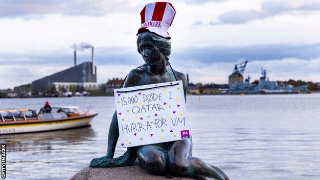 The Little Mermaid statue in Copenhagen with a protest sign