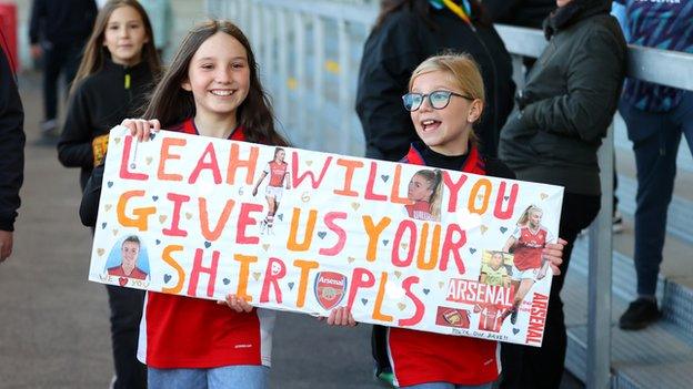 Two girls hold a banner asking for Leah Williamson's shirt