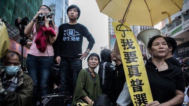 Civic Party lawmaker Claudia Mo (C) stand with pro-democracy protesters on a makeshift stage as bailiffs remove tents under a court injunction in the Mongkok district of Hong Kong on November 25, 2014.