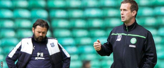 Dundee manager Paul Hartley looks dejected, while Ronny Deila watches the action at Celtic Park