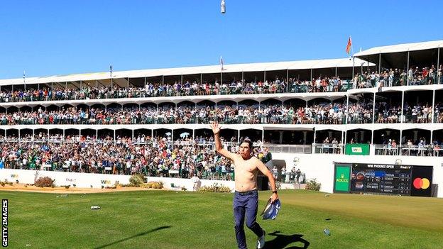 Shirtless PGA Tour professional Joel Dahmen tosses a beer can in the air while playing the 16th at TPC Scottsdale