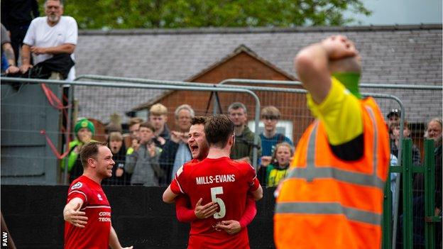 Newtown celebrate while fans look on from outside the ground