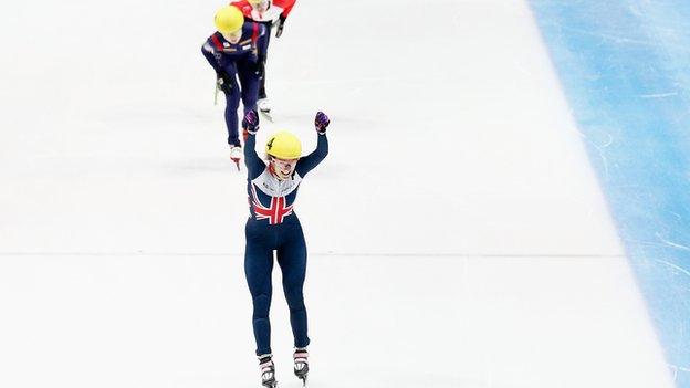 Elise Christie raises her arms aloft after winning the 1000m in Dordrecht