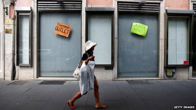 A woman walks past closed shops in Italy