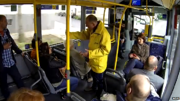 A shot from the hidden camera of the bus conductor asking two women to move