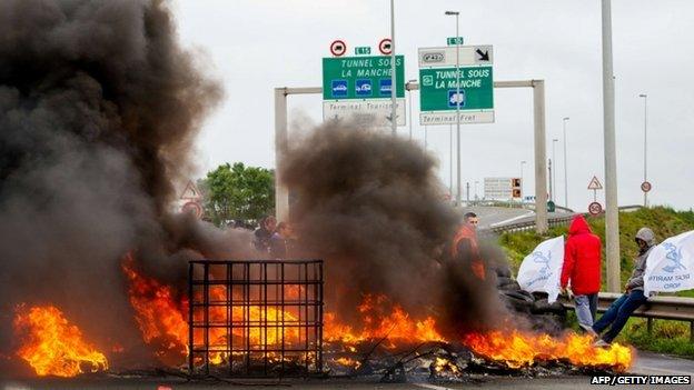 Striking employees of the French company MyFerryLink stand in front of a tyre fire