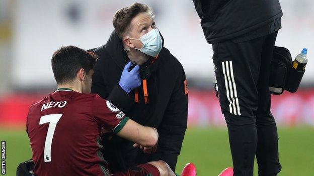 Wolves forward Pedro Neto receives treatment from a physio for a knee injury against Fulham