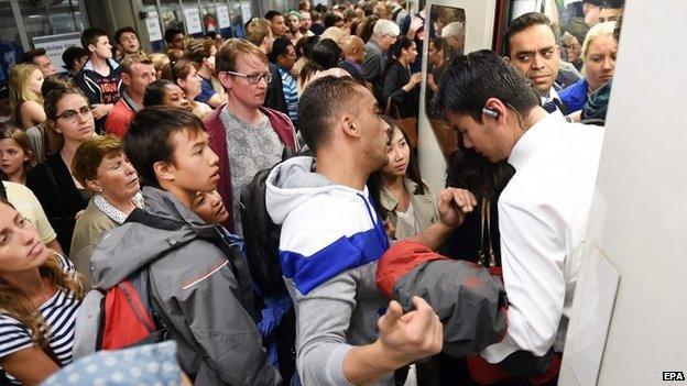 Commuters try to get onto a tube train at Westminster station in July