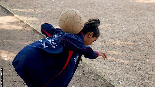 Saini juggles a football on her back