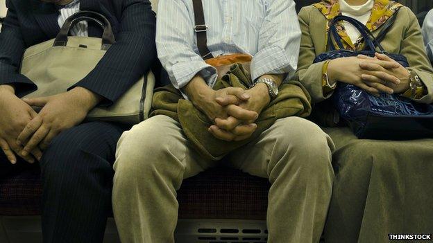 A man sitting between two others on a train