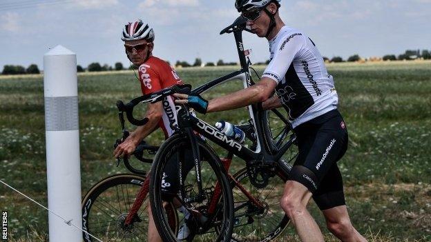 Chris Froome lifts his bike back on to the road after crashing on stage one