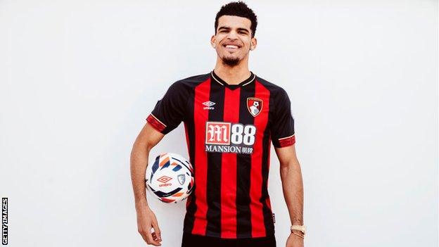 Striker Dominic Solanke smiles while holding a football and wearing a Bournemouth shirt following his move from Liverpool