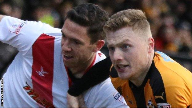 Ben Tozer of Newport County and Cambridge United's George Maris tussle as they chase the ball