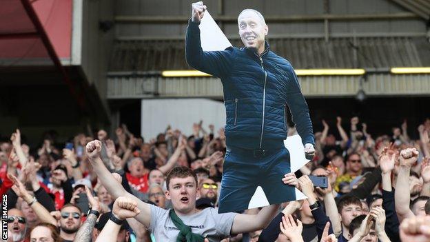 Nottingham Forest fans holding a cardboard cut-out of Steve Cooper