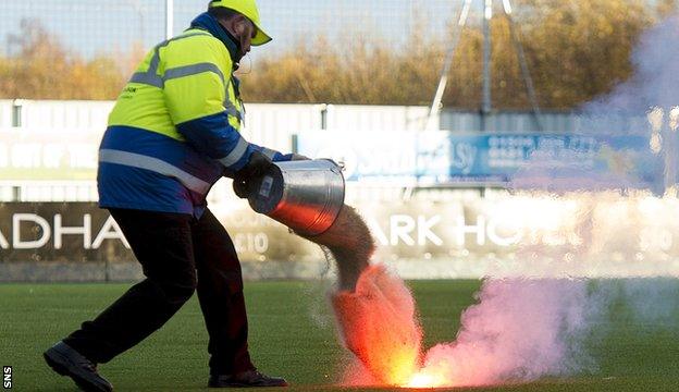 A steward puts out a flare thrown on to Falkirk's artificial pitch