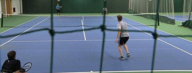 Able-bodied and wheelchair doubles much in an indoor tennis court