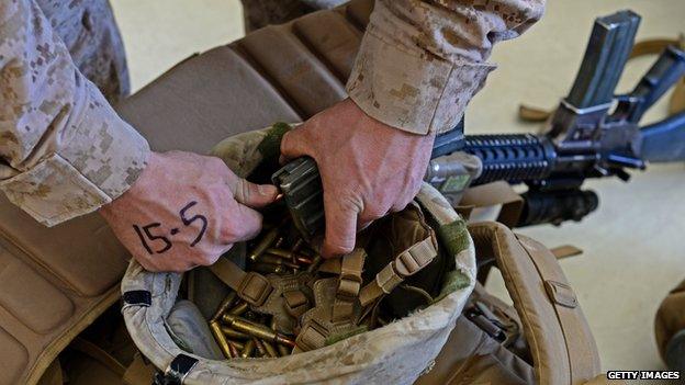 A US Marine unloads ammunition from a rifle magazine into his helmet after arriving in Kandahar