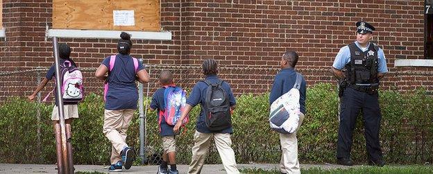 A police officer watches as children walk home from Laura Ward Elementary school in Chicago in 2013.