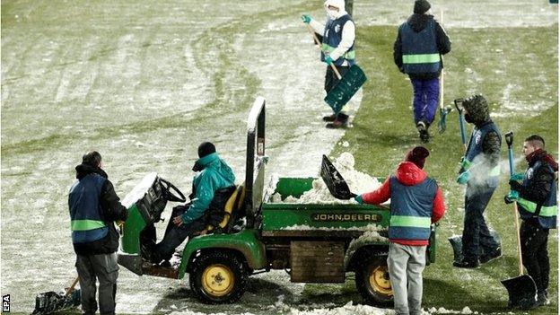 Ground staff clearing the pitch of snow at Osasuna