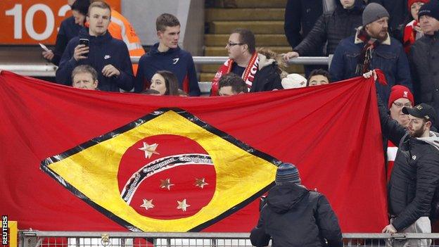 Liverpool fans carry a flag with Chapecoense team named on it