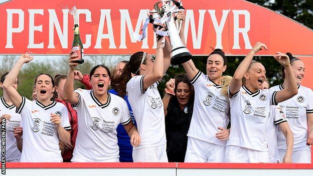 Swansea City players celebrate after being presented with the Genero Adran Premier trophy.