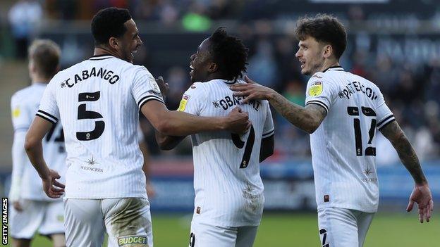 Miochael Obafemi celebrates with Swansea team-mates Ben Cabango and Jamie Paterson