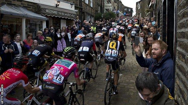 Cylists ride on a cobblestone street through the village of Haworth, Yorkshire