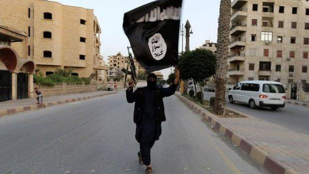 A member loyal to the Islamic State in Iraq and the Levant (ISIL) waves an ISIL flag in Raqqa June 29, 2014.