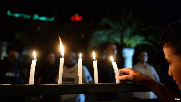 A boy arranges candle lights on a fence in front of the Hotel Imperial Marhaba in Sousse, Tunisia