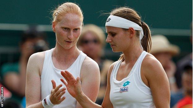 Belgian couple Alison van Uytvanck (left) and Greet Minnen (right) high five during a doubles match at Wimbledon