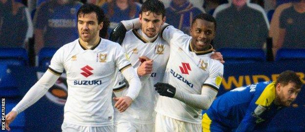 MK Dons players celebrate a goal against AFC Wimbledon