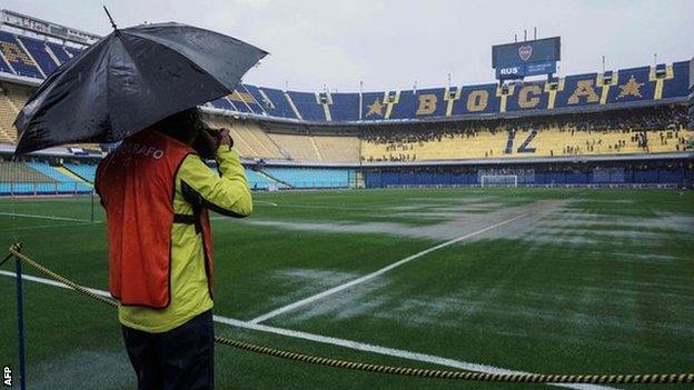 Photographer takes picture of waterlogged pitch at Boca's La Bombonera stadium.