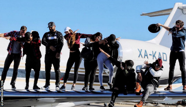 Lewis Hamilton and friends pose for a photo on the wing of a plane