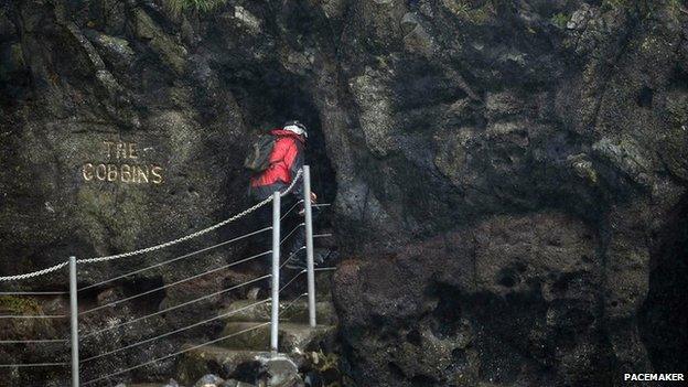 Walker enters cave along Gobbins path