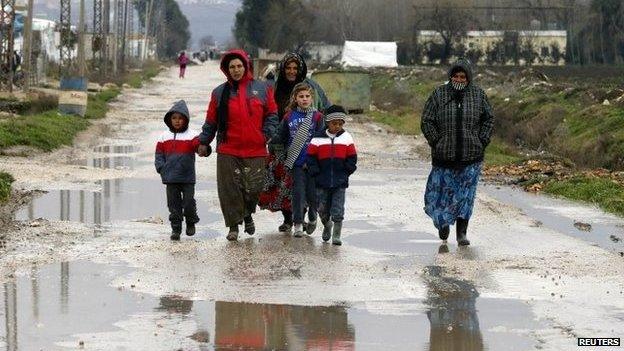 Syrian refugees walk along a makeshift settlement in Bar Elias in the Bekaa valley January 5, 2015